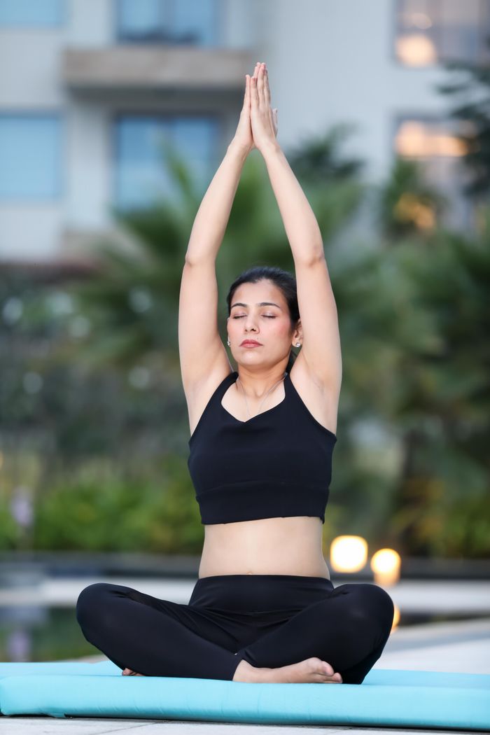 our-experience Adult woman meditating in outdoor setting, engaging in a serene yoga session to promote relaxation and wellness.